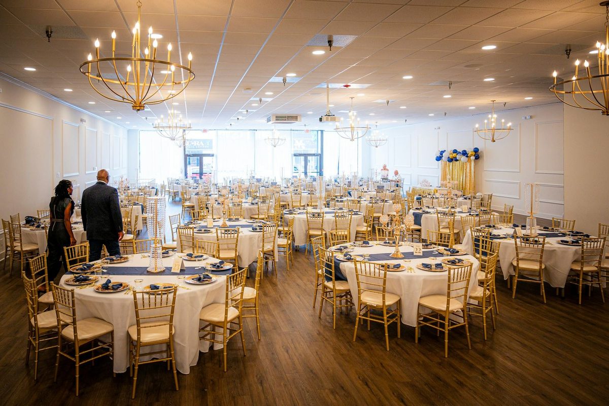 A banquet hall set with round tables and chandeliers